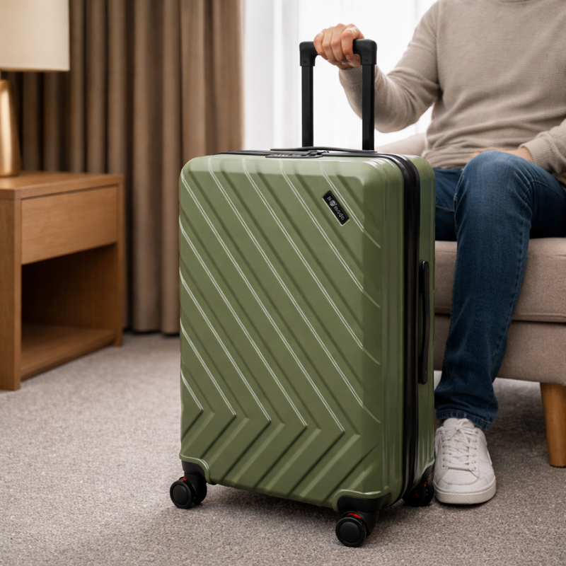 Green Nomado suitcase with a telescopic handle and pattern in a room with a seated person