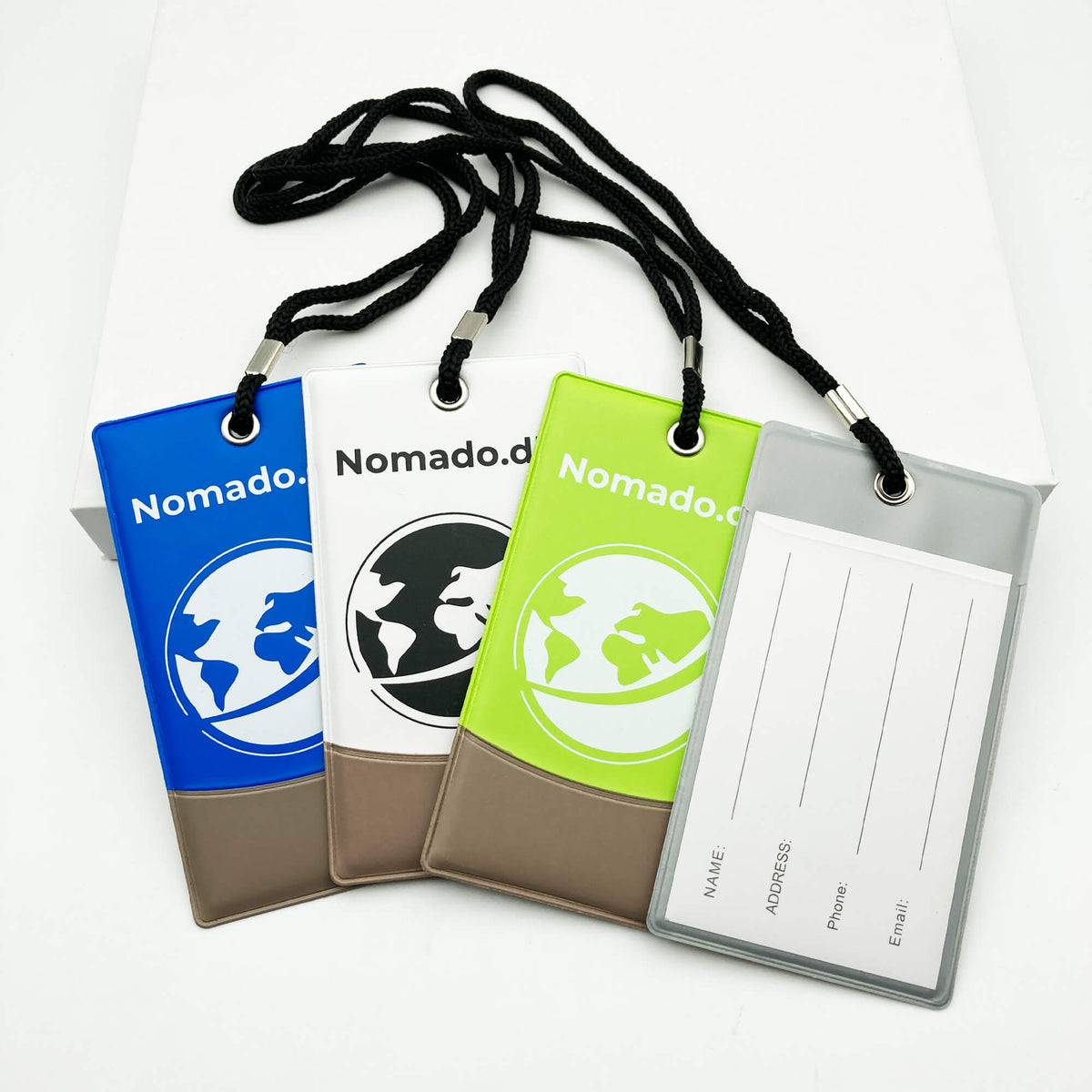 Nomado luggage tags in blue, white and green with a globe logo and contact information