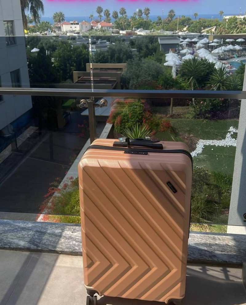 Nomado Horizon suitcase on a balcony with a beautiful sea view